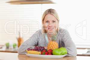 Woman sitting in the kitchen with a plate of fruits