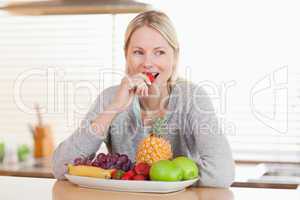 Woman in the kitchen nibbling some fruits