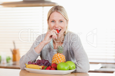Woman in the kitchen eating a strawberry