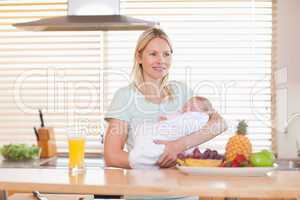 Woman standing in the kitchen holding her baby