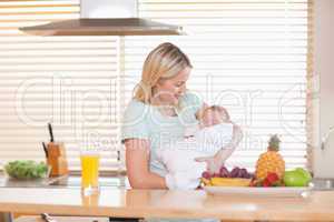 Woman holding her sleeping baby in the kitchen