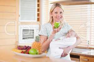 Smiling woman with an apple and her baby on her arms