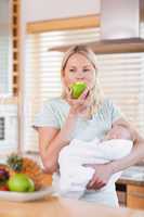 Woman with baby on her arms having an apple