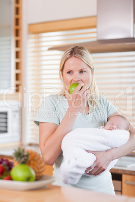 Female with baby on her arm having an apple