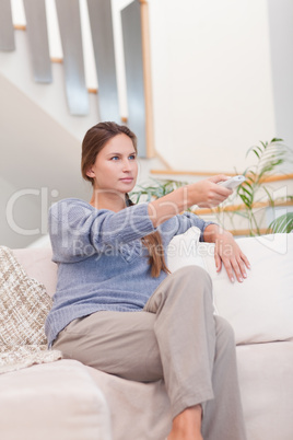 Portrait of a woman switching channel with a remote