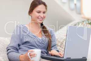 Woman using a laptop while having a tea