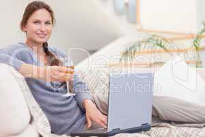 Woman having a glass of wine while using her laptop