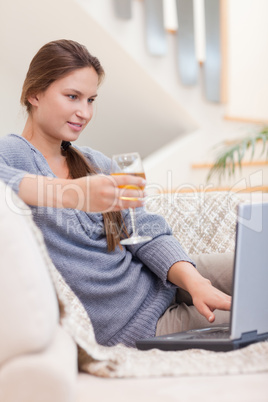 Portrait of a woman having a glass of white wine while using her