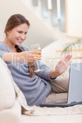 Portrait of a woman having a glass of white wine during a video