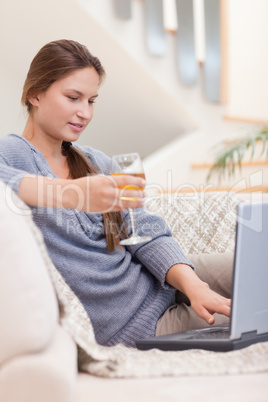 Portrait of a woman having a glass of wine while using her noteb