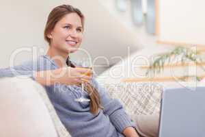 Woman having a glass of wine while using her notebook