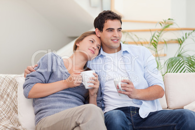 Lovely couple watching TV while drinking tea