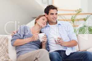 Lovely couple watching TV while drinking tea