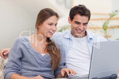 Delighted couple using a laptop