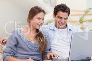 Delighted couple using a laptop