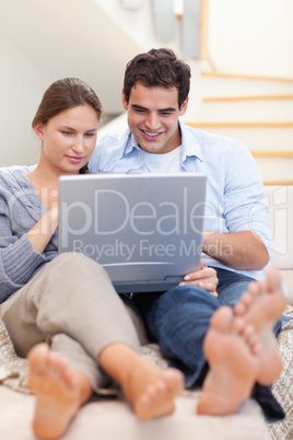 Portrait of a couple using a laptop while lying on a couch