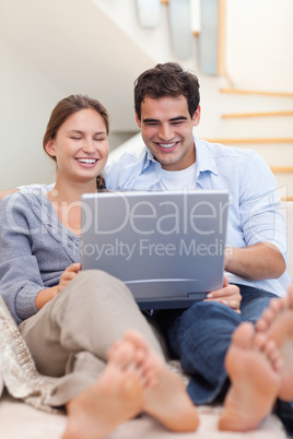 Portrait of a couple using a laptop while lying on a sofa