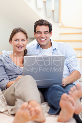 Portrait of a couple using a notebook while lying on a sofa