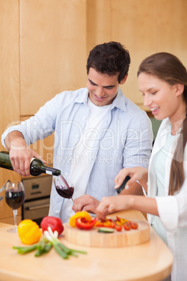 Portrait of a cute man pouring a glass of wine while his wife is