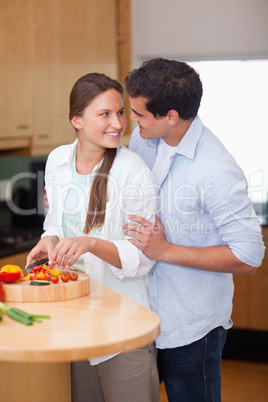 Portrait of a man hugging his wife while she is cooking