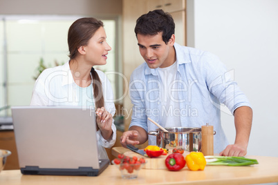 Couple using a notebook to cook