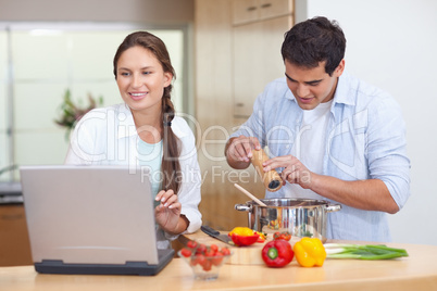 Young couple using a notebook to cook