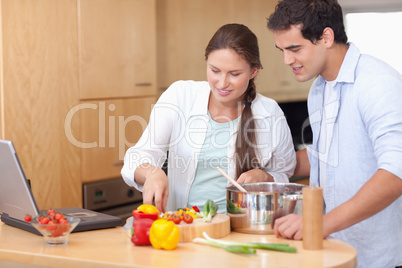 Happy couple using a laptop to cook
