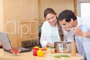 Gourmet couple using a laptop to cook