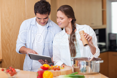 In love couple using a tablet computer to cook