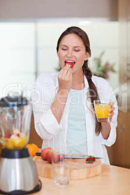 Portrait of a woman eating a fresh strawberry