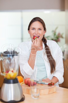 Portrait of a woman eating a strawberry
