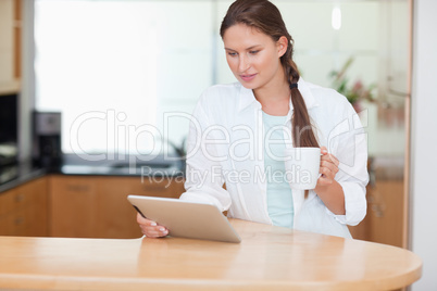 Woman using a tablet computer while drinking tea