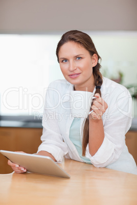 Portrait of a woman using a tablet computer while drinking coffe