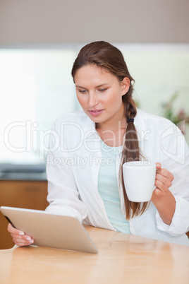 Portrait of a young woman using a tablet computer while drinking