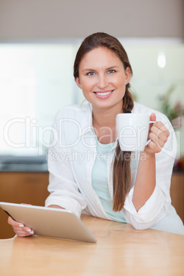 Portrait of a young woman using a tablet computer while drinking