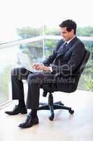 Portrait of a businessman sitting on an armchair working with a