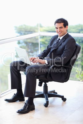 Portrait of a young businessman sitting on an armchair working w