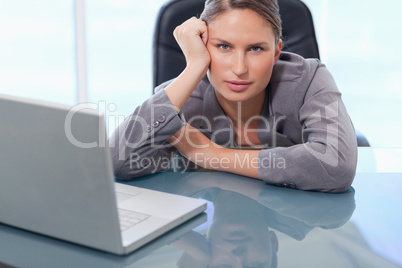 Serious businesswoman leaning on her desk