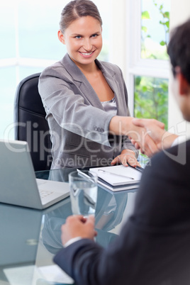 Smiling businesswoman welcomes customer in her office