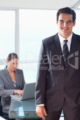 Smiling tradesman with working colleague behind him