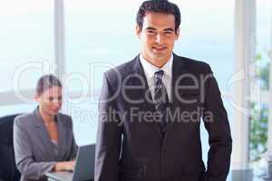 Smiling businessman with colleague behind him