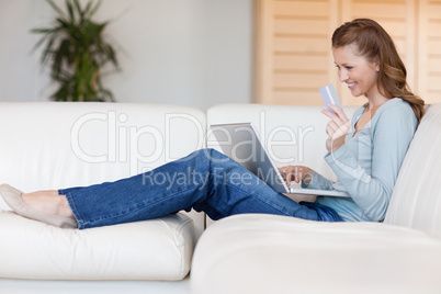 Woman booking flight online on her sofa