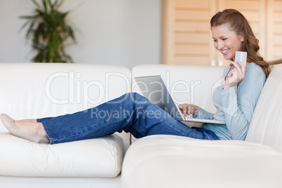Happy woman booking flight online on the sofa