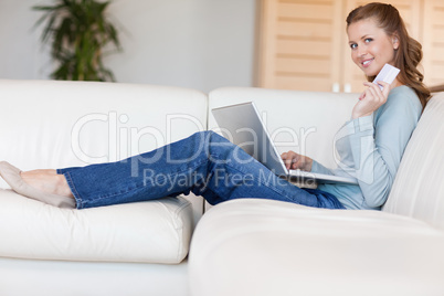 Young woman on the sofa booking a flight online