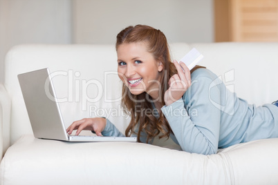 Smiling woman on the sofa using her credit card online