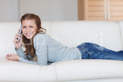 Cheerful smiling woman on the sofa with the phone