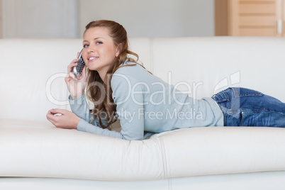 Female lying on the sofa, listening closely to the phone