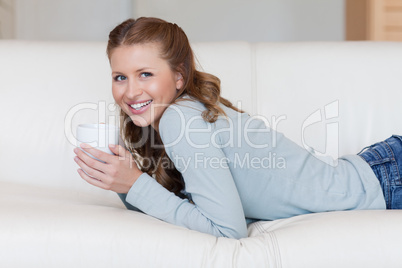 Young female enjoying a coffee break on her sofa