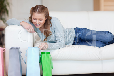 Young female on the sofa looking into her shopping bags