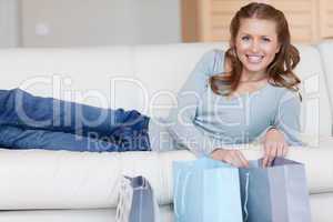 Smiling female lying next to her shopping